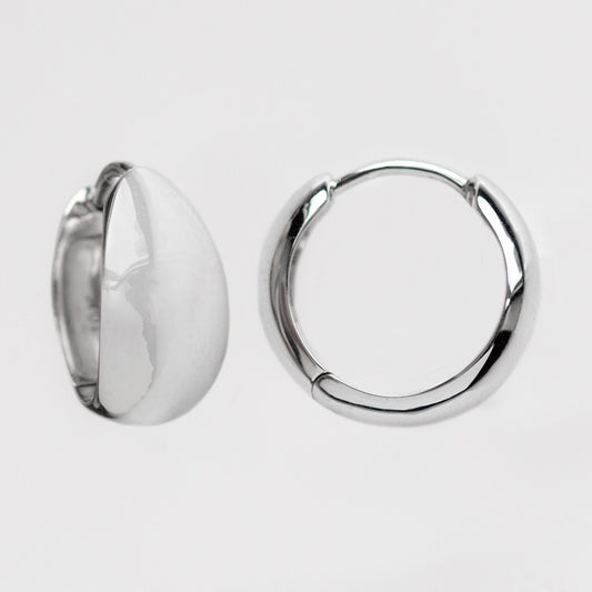 Two Solid Gold Chunky Huggie Hoops are displayed on a plain white background; one earring is shown from the side to highlight its thickness, while the other is shown from the front.